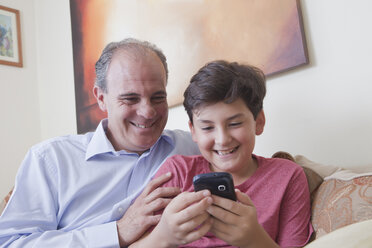 Hispanischer Vater und Sohn schreiben eine SMS mit dem Handy - BLEF04639