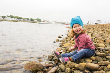 Smiling Caucasian girl sitting on rocks at river - BLEF04691