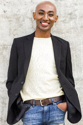 Smiling gay Black man leaning on concrete wall - BLEF04707