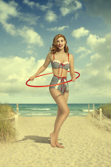 Kaukasische Frau im Bikini hält Plastikreifen am Strand - BLEF04765