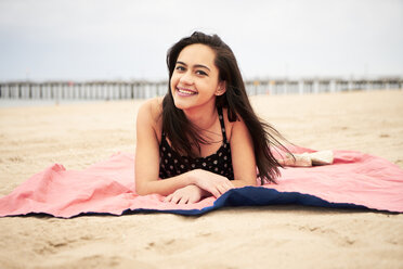 Mixed Race woman laying on blanket at beach - BLEF04795