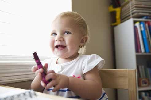 Lächelndes kaukasisches Babymädchen mit Buntstift - BLEF04826