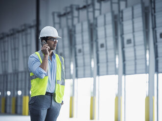 Indischer Arbeiter, der an der Laderampe mit seinem Handy telefoniert - BLEF04854