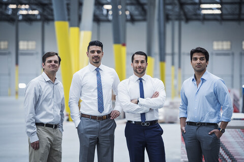 Smiling businessmen posing in empty warehouse stock photo