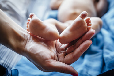 Hispanic woman holding feet of baby boy - BLEF04898