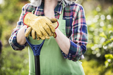 Kaukasische Frau mit Handschuhen hält Schaufel - BLEF04980