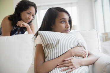 Mutter beobachtet nachdenkliche Tochter, die sich an ein Kissen klammert - BLEF05032