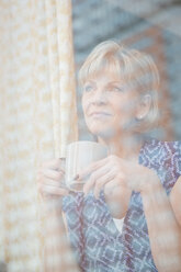 Older Caucasian woman drinking coffee at window - BLEF05046