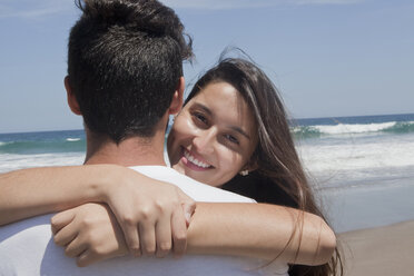 Hispanisches Paar, das sich am Strand umarmt - BLEF05099