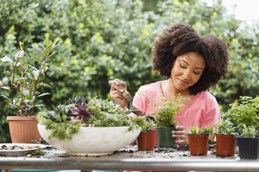 Schwarze Frau bei der Gartenarbeit am Tisch im Freien - BLEF05109