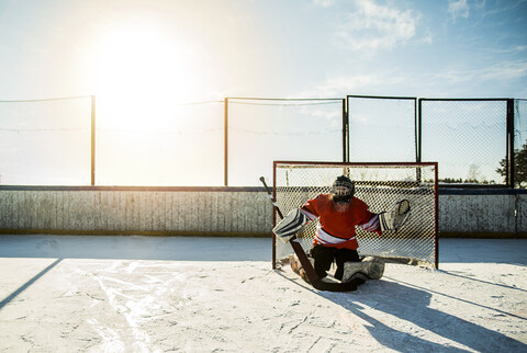 Kaukasischer Junge spielt Torwart beim Eishockey im Freien, lizenzfreies Stockfoto