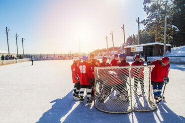 Kaukasische Jungen um den Torwart beim Eishockey im Freien - BLEF05124