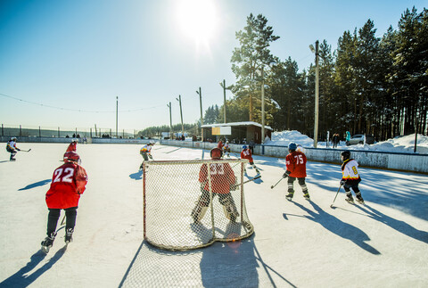 Kaukasische Jungen spielen Eishockey im Freien, lizenzfreies Stockfoto