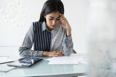 Indian businesswoman reading paperwork in office - BLEF05177