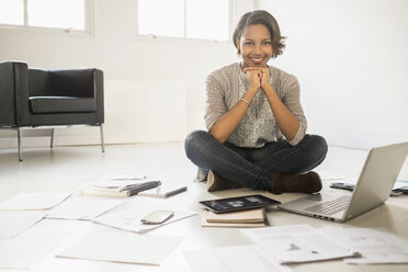 Black businesswoman smiling with laptop and digital tablet on floor - BLEF05211