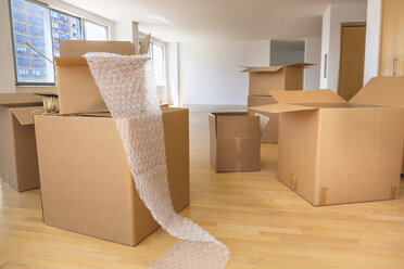 Cardboard boxes and bubble wrap in empty apartment - BLEF05237