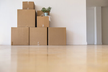 Cardboard boxes stacked against wall in empty apartment - BLEF05239