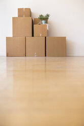 Cardboard boxes stacked against wall in empty apartment - BLEF05240