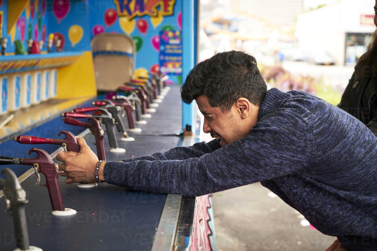 Man playing shooting game at amusement park stock photo