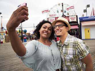 Couple posing for selfie on boardwalk at amusement park - BLEF05266