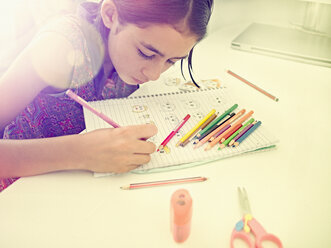 Mixed Race girl drawing faces in notebook - BLEF05292