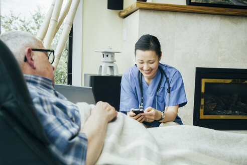 Krankenschwester schreibt in der Nähe eines Patienten eine SMS mit dem Handy - BLEF05298