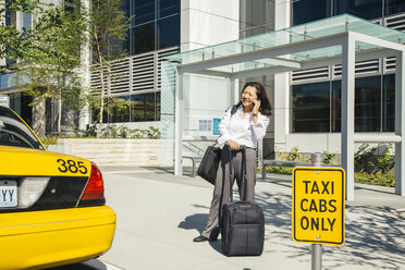 Businesswoman talking on cell phone near taxi - BLEF05313