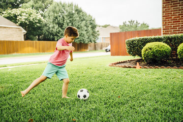 Caucasian boy kicking soccer ball on lawn - BLEF05331