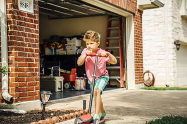 Caucasian boy riding push scooter in driveway - BLEF05332