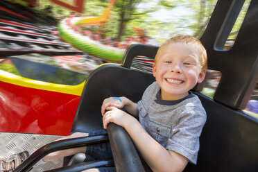 Caucasian boy smiling on amusement park ride - BLEF05356