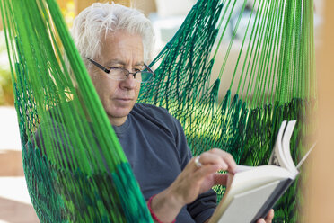 Caucasian man reading book in green hammock - BLEF05367