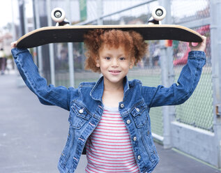 Girl holding skateboard in urban park - BLEF05429