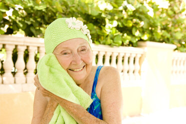 Ältere kaukasische Frau, die sich nach dem Schwimmen mit einem Handtuch abtrocknet - BLEF05434