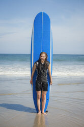 Caucasian girl holding paddleboard on beach - BLEF05446