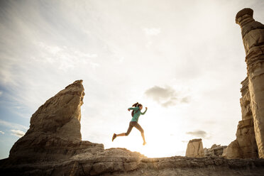 Woman running in canyon wearing backpack - BLEF05498