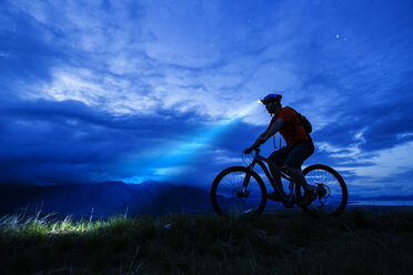 Silhouette eines kaukasischen Mannes auf einem Mountainbike bei Nacht - BLEF05501