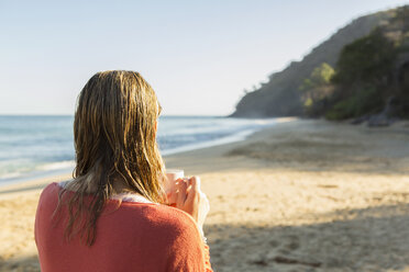 Caucasian woman drinking coffee on beach - BLEF05507