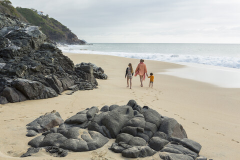 Kaukasische Mutter und Kinder gehen am Strand spazieren, lizenzfreies Stockfoto