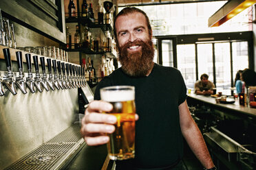 Lächelnder kaukasischer Barkeeper serviert Bier an der Bar - BLEF05566