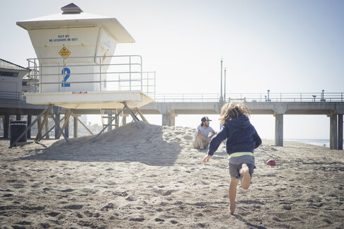 Kaukasischer Junge läuft am Strand zum Vater - BLEF05580