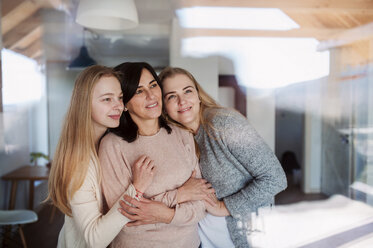 Visiting daughters embracing their mother, standing at the window - HAPF02887