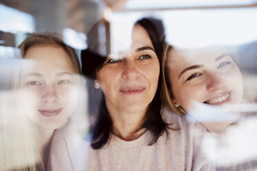 Visiting daughters embracing their mother, standing at the window - HAPF02888