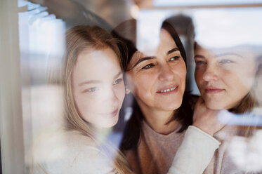 Visiting daughters embracing their mother, standing at the window - HAPF02889