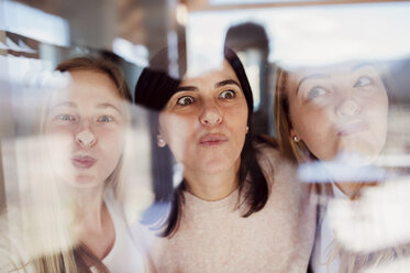 Mother and daughters pressing noses against window pane - HAPF02890