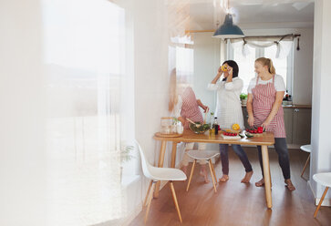 Mother and daughters standing in kitchen, preparing food, chopping vegetables - HAPF02897