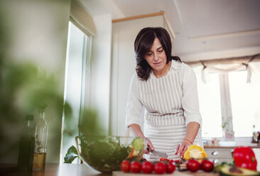 Mature woman preparing salad in her kitchen - HAPF02903