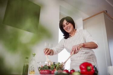 Mature woman preparing salad in her kitchen - HAPF02904