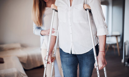 Daughter helping her mother to walk with crutches - HAPF02929