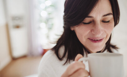 Reife Frau in einem Badezimmer zu Hause, die eine Tasse Kaffee genießt - HAPF02945