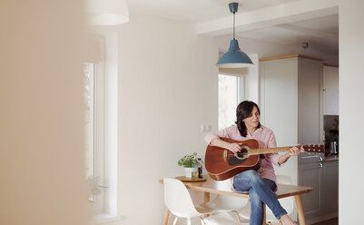 Mature woman playing guitar at home - HAPF02956